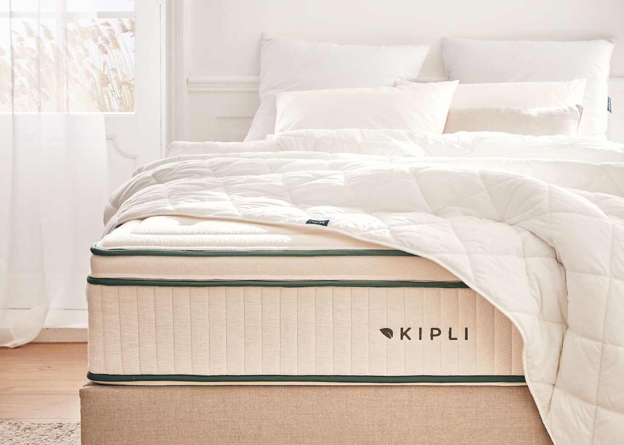 Matelas Kipli en latex naturel avec couette et oreillers blancs, illustrant une literie saine et durable dans une chambre lumineuse.