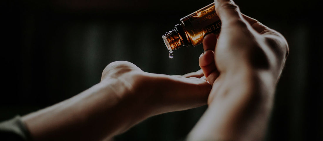 Goutte d’huile essentielle versée dans la paume de la main, en gros plan.