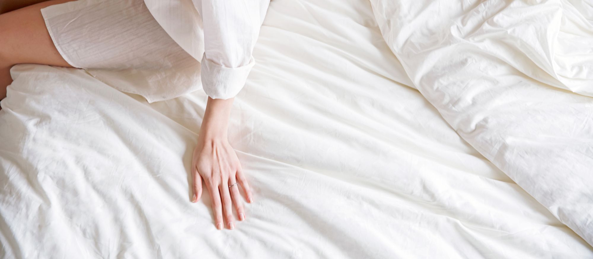 Main posée sur un linge de lit en coton bio blanc, illustrant la douceur et la qualité de la parure de lit Kipli.